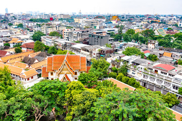 Fototapeta premium Panorama view of Bangkok city, Thailand. Cityscape of residental buildings in foreground, temples, skyscrapers and modern buildings in far. Fresh trees and plants. Cloudy weather, dramatic clouds.