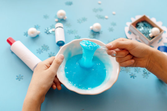 a girl making slime herself. child making slime on blue Christmas background. 