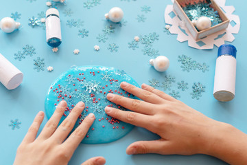 a girl making slime herself. child making slime on blue Christmas background. 