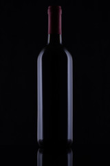 Black glass bottle of red wine on black background