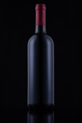 Black glass bottle of red wine on black background