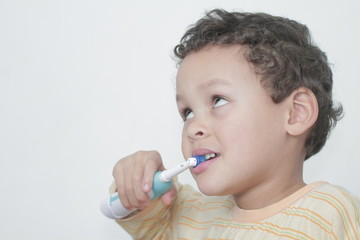 little boy brushing his teeth with an electric tooth brush stock image with grey background stock photo