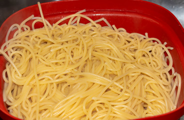 cooked spaghetti in a red bowl / close-up