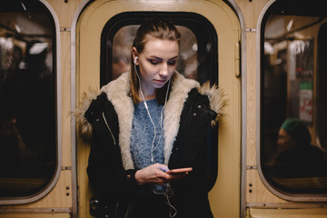 Young woman using smart phone while traveling in subway train