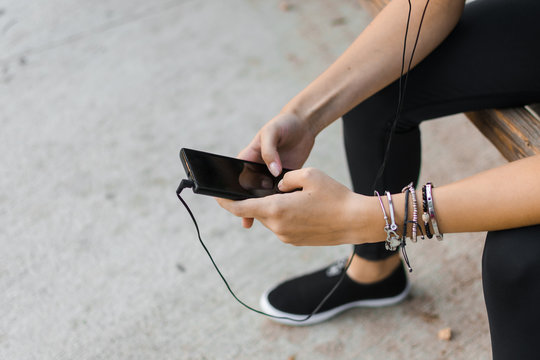 Young woman is looking her smartphone while she is sitting. Close up