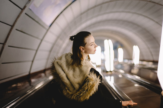Young woman standing on escalator at subway station