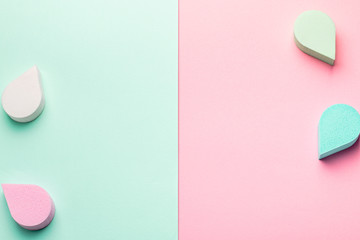 Beauty, make up sponges or beauty blenders in pastel colors on two color background, copy space, top view. Beauty background