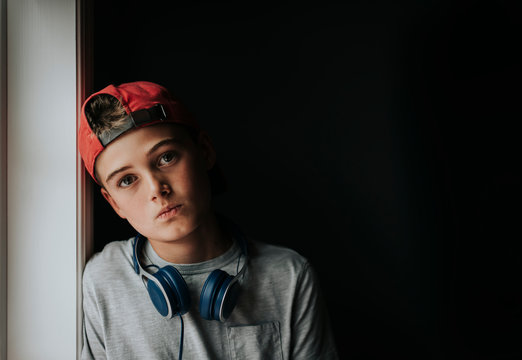 Portrait of tween boy with headphones around neck and backwards hat.