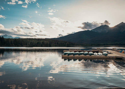 Line of canoes on a dock at sunset on Pyramid Lake in Jasper, Alberta.