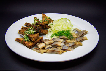 Croutons with herring on black background