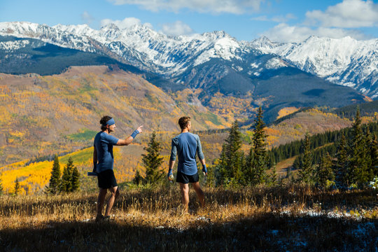 Men on trail run look at Gore Range mountains from Vail, Colorado