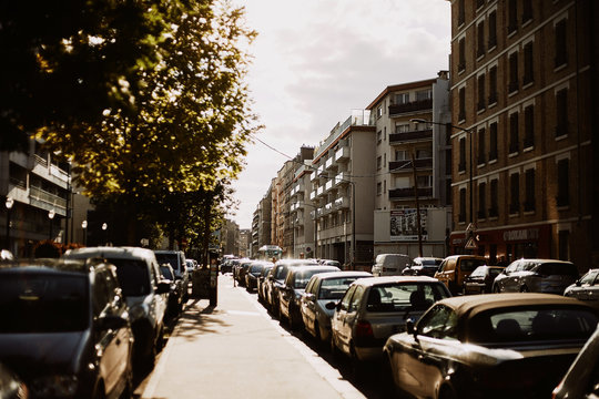 Sunny street of Paris, France, with the cars and cloudy sky