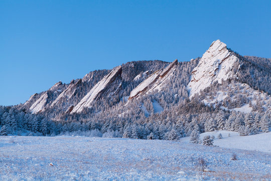 Flatirons and meadow in snow at dawn above Boulder, Colorado