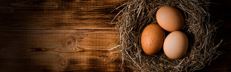 Chicken eggs in wicker nests in chicken coop top view. Natural organic eggs in the hay. Fresh...