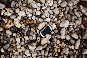 Smartphone laying on the pebble shore