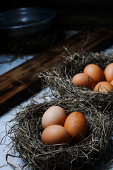 Chicken eggs in wicker nests in chicken coop top view. Natural organic eggs in the hay. Fresh chicken eggs.