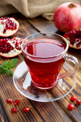 Pomegranate tea in the glass cup the  rustic wooden background. Location vertical.