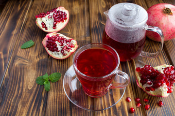 Pomegranate tea in the glass cup and teapot on the brown wooden background