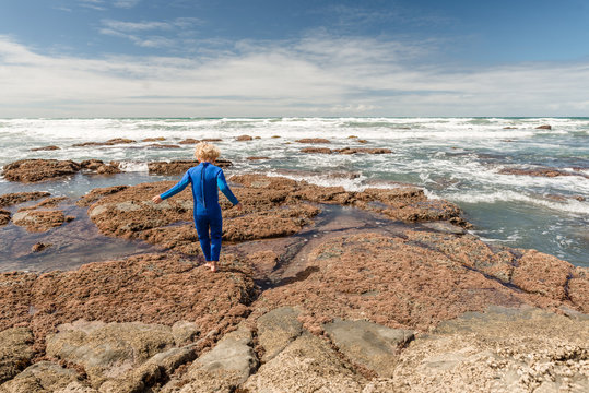 Small child walking on rocks near the ocean