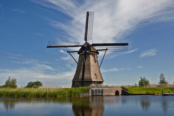 Windmills across and reflected in water in Kinderdijk district popular tourist destination with it's scenic fields, dykes, ponds, canals and windmills near Rotterdam, Holland.