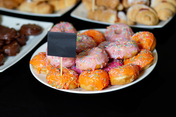 Plate with fresh donuts, multicolored and sprinkled with beautiful sprinkles.