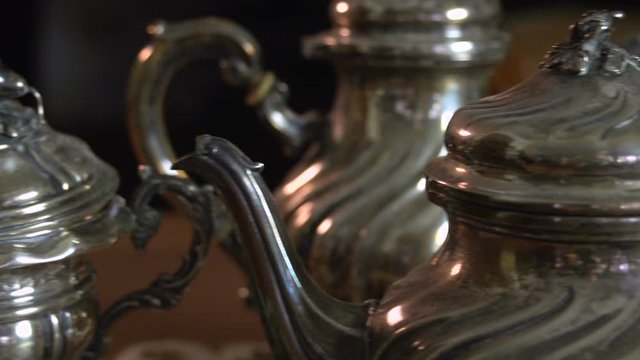 Very close up panning on vintage silverware tea set wth tea pot, sugar bowl and milk pan  FDV