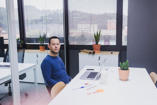 Portrait of young man sitting at his desk in the office