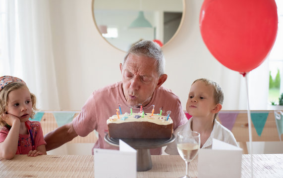 grandad sat with his grandchildren on his birthday blowing candles