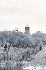 View to ancient Turaida castle standing in snowy trees with river Gauja in foreground on a beautiful winter day in December in Sigulda in Latvia