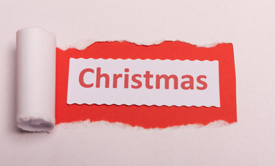 White torn paper with CHristmas text with red background color. Hidden message. Secret. Copy space.