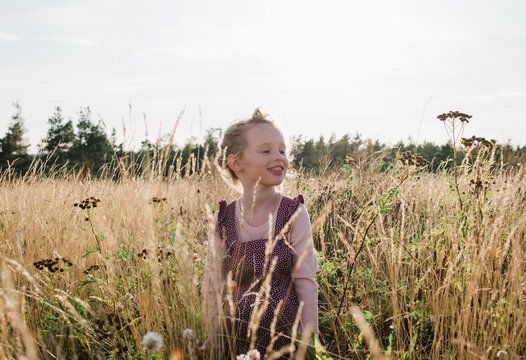 portrait of a young girl smiling sitting in a meadow of wild flowers