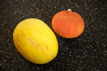 Colorful round cucurbits on dark speckled background. Pumpkin and melon oval shape still life....