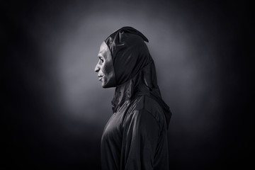 Fototapeta na wymiar Scary figure in hooded cloak with mask 