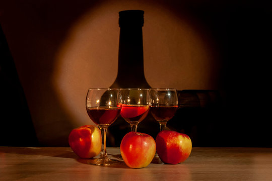 Three glasses with calvados and apples on the table on the background of the bottle