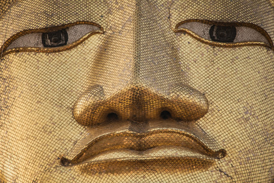 Detail of the giant standing Buddha face at Wat Intharawihan temple