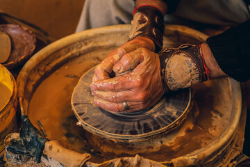 The master forms a clay cup on a potter's wheel. A potter's hands preparing a clay pot. Close-up.
