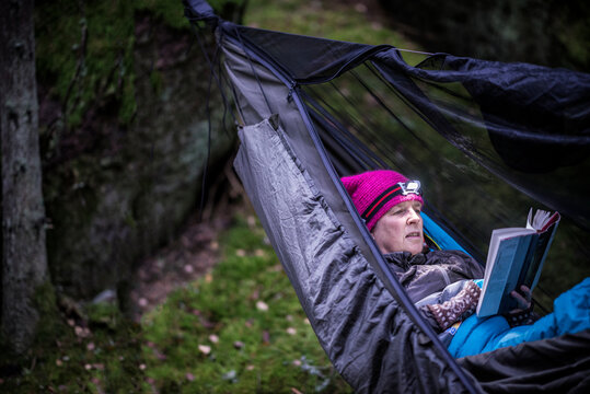 Woman reading book in hammock in forest