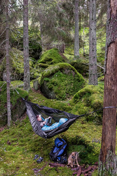 Woman reading book in hammock in forest