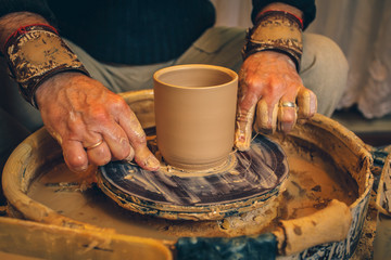 The master forms a clay cup on a potter's wheel. A potter's hands preparing a clay pot. Close-up.