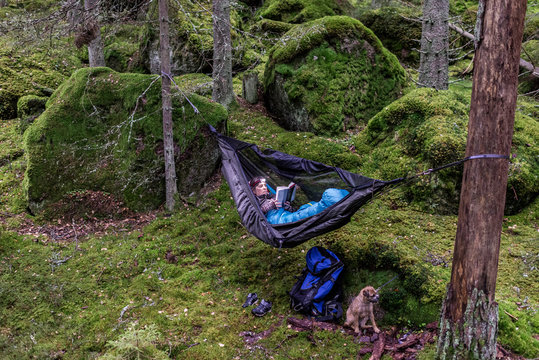 Woman reading book in hammock in forest