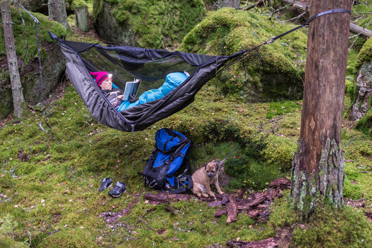 Woman reading book in hammock in forest