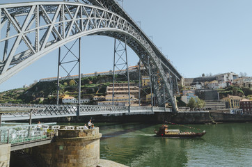 View on the Dom Luis I bridge with a boat sailing and Villa Nova de Gaia district