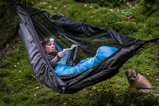 Woman reading book in hammock in forest