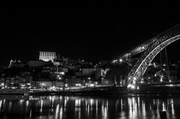 Fototapeta na wymiar Night view in black in white of the Dom Luis I bridge from the Villa Nova de Gaia dock
