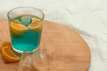 Blue alcoholic drink with ice and sliced oranges on wooden board. Create your own style.  Drink.