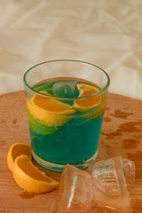 Blue alcoholic drink on the wooden board. With orange and ice. Refreshing cocktail.  Cold summer drink.  Home.