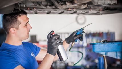Car master mechanic repairer lubricates screws with machine cleaner spray
