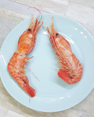 Fresh and tasty boiled wild king prawns with on plate ready for eating. Big red shrimps.