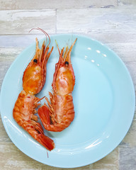 Seafood boiled wild tiger prawns close up on a blue plate on the table. the view from the top.