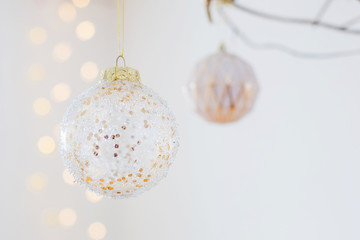 Christmas balls on golden branch in white interior
